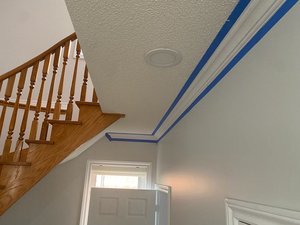 Crown moulding stopping at the sloped ceiling above an open staircase