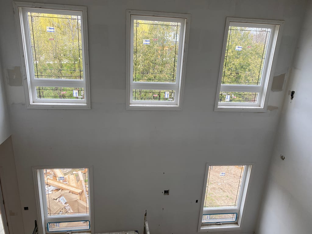 Tall window trim installation on a two-storey wall in an Oakville custom home
