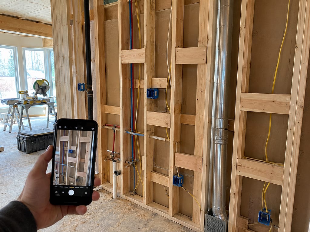 Open framed wall with electrical wiring, plumbing, HVAC ductwork and wood blocking photographed before drywall