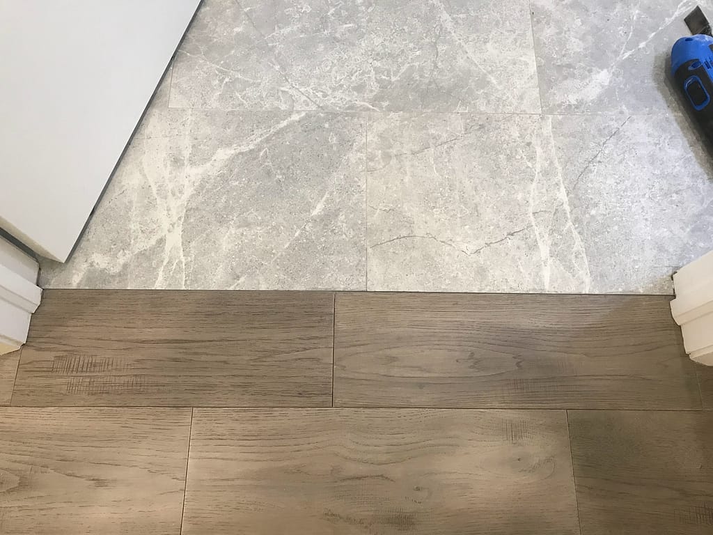 Completed engineered hardwood floor repair beside a tile transition in Mississauga