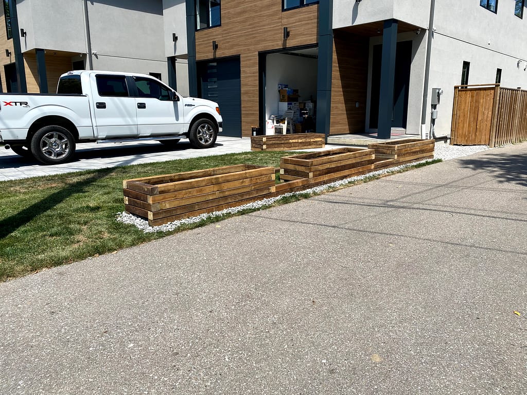 Four custom raised wooden planter boxes installed outside Mississauga homes