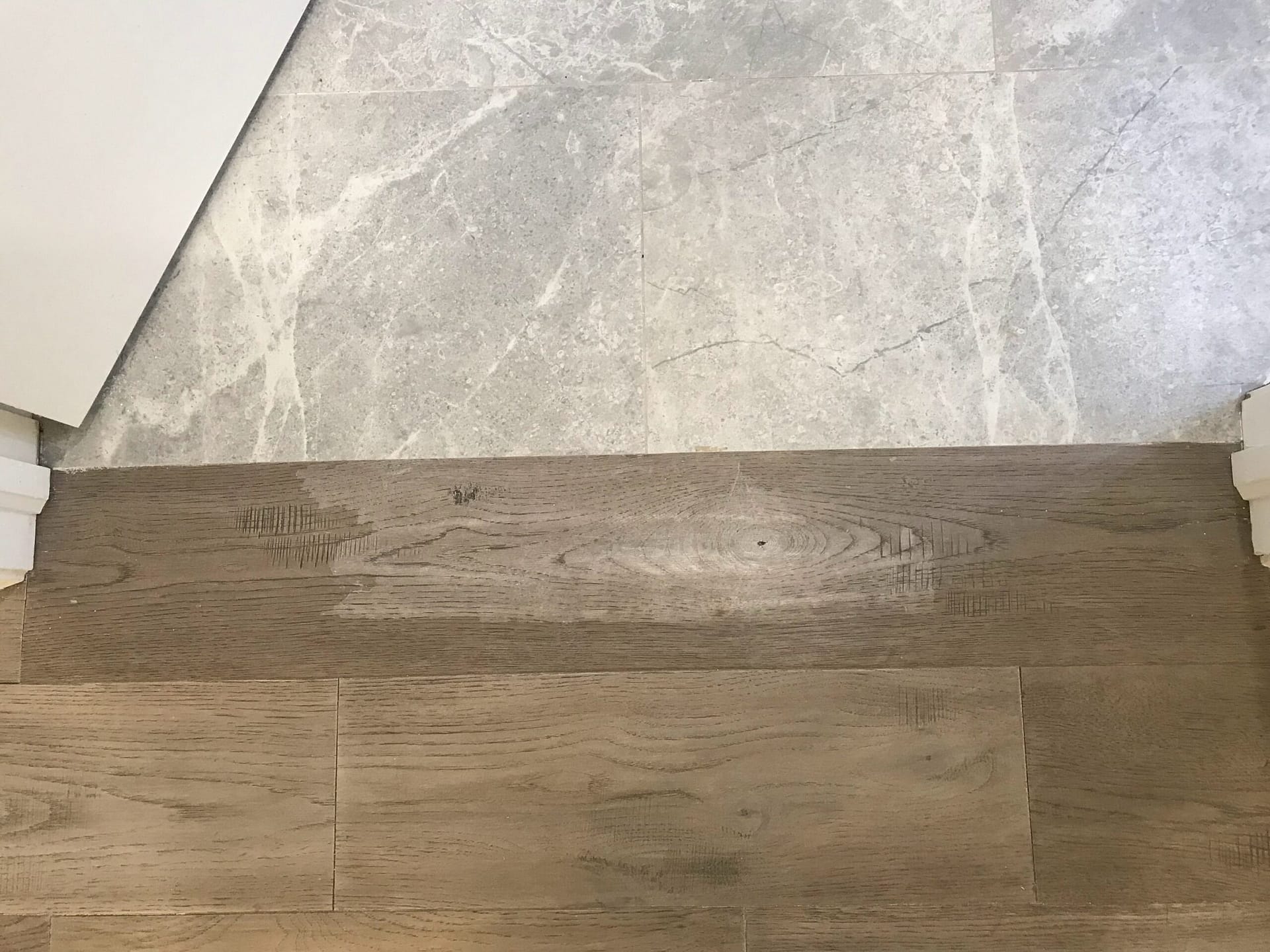 Damaged engineered hardwood planks near a tile transition in a Mississauga home