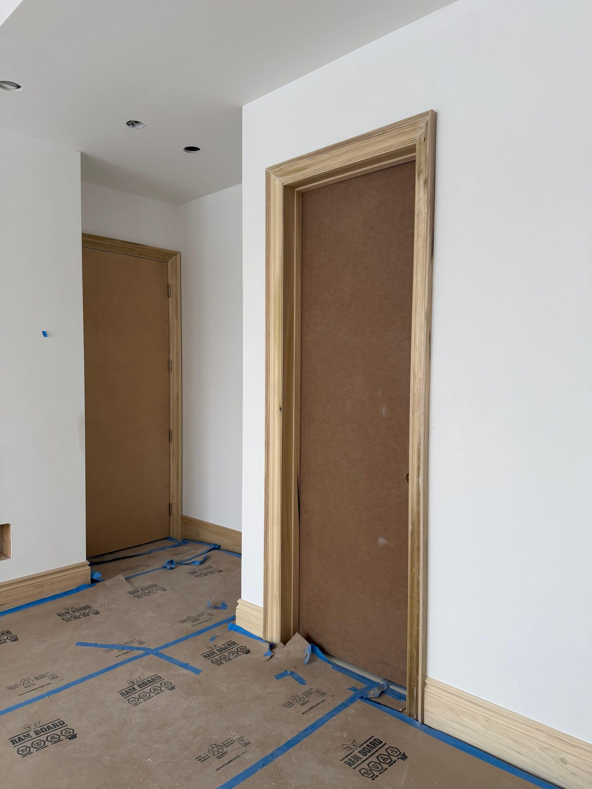 Two 96-inch solid-core interior doors installed with casing and baseboards beside a bedroom and bathroom
