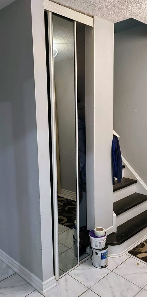 Floor-to-ceiling mirrored sliding closet door beside the staircase in a Milton home entryway