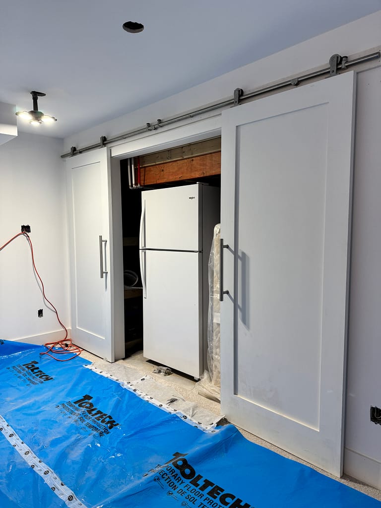 Twin barn doors installed by a finish carpenter for hidden utility access