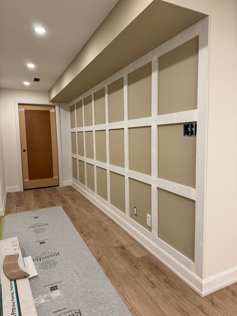 Board and batten wall paneling installed in a Milton basement with baseboards and door trim nearby.