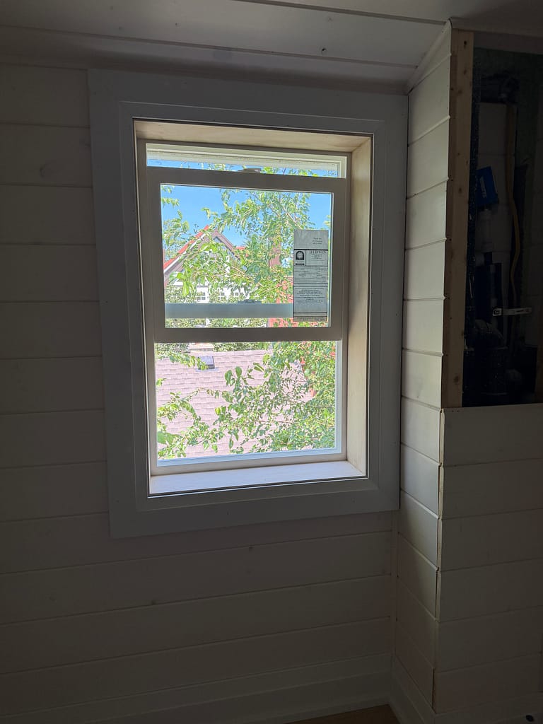 Bathroom window finished with jamb extensions and casing in a shiplap attic wall