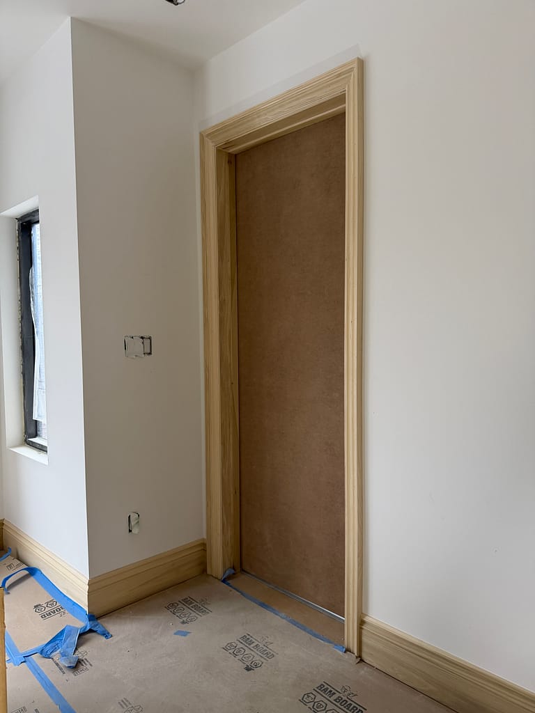 Tall interior door with natural wood casing and baseboard in a Toronto custom home