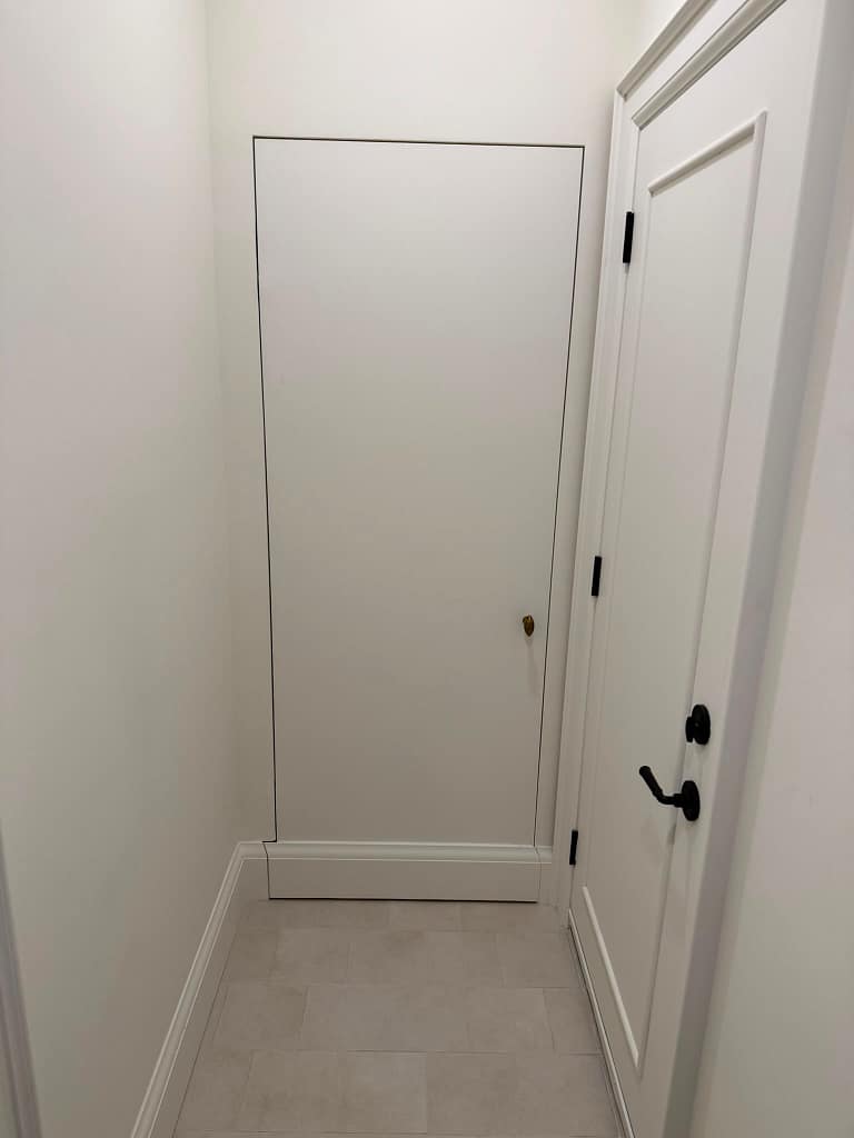 Finished fire-rated interior door with applied molding, black hardware, and custom casing.