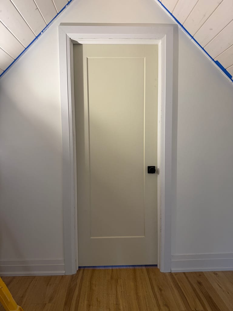 One-panel interior door installed with casing beneath a sloped attic ceiling