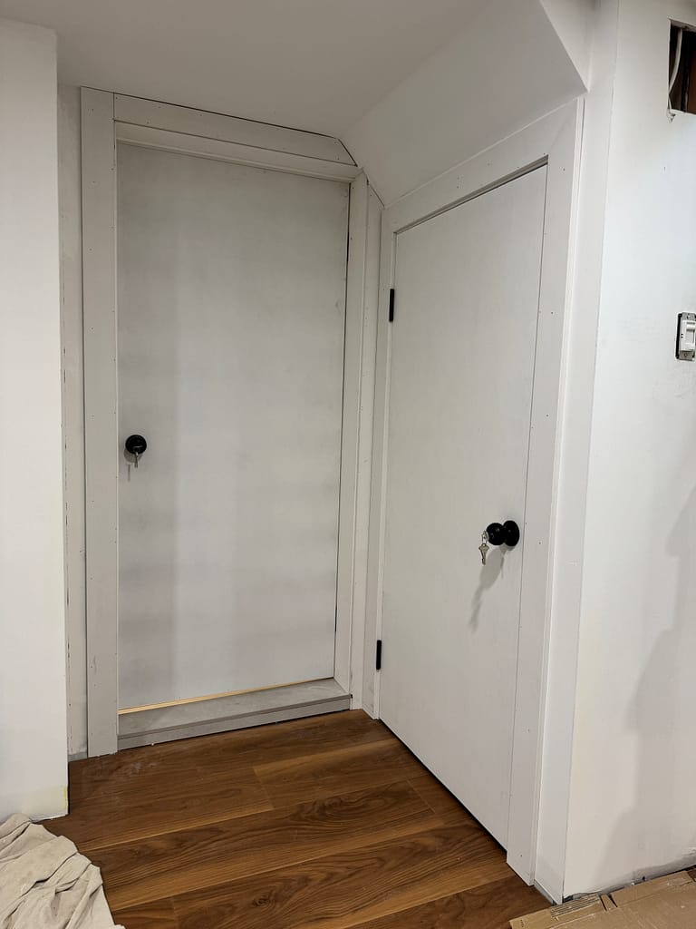 Custom basement door installed with casing fitted around a tight opening.