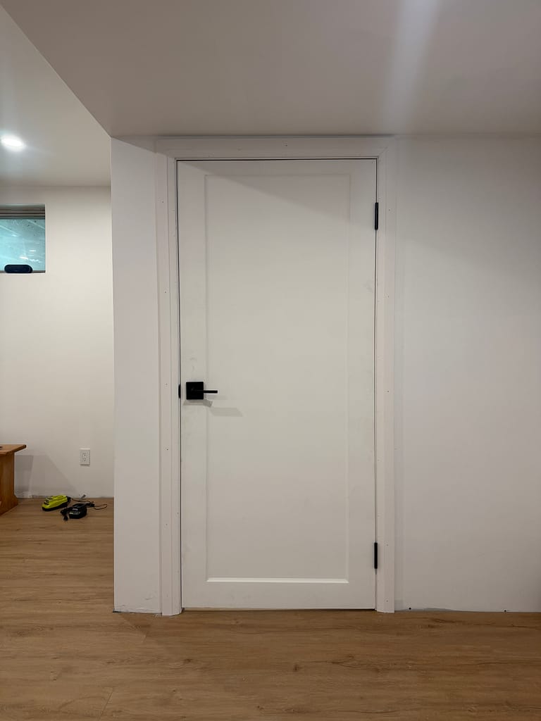 White one-panel basement washroom door with black hardware installed in Burlington