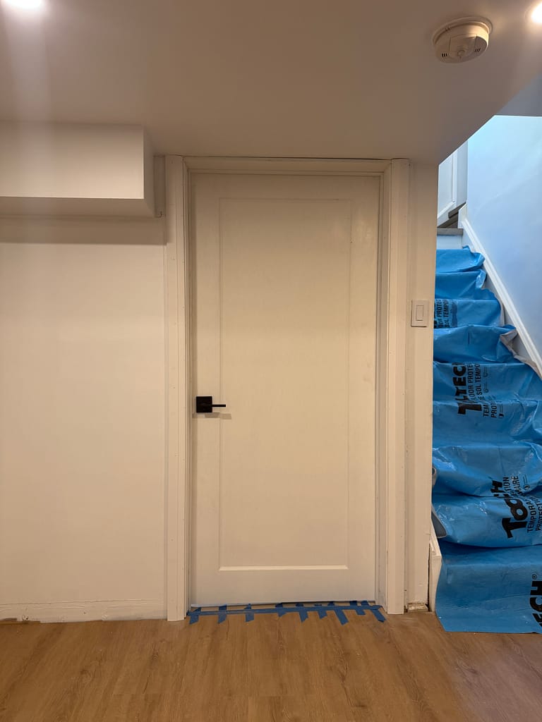 Basement laundry and utility-room door installed beside the stairs in a Burlington home
