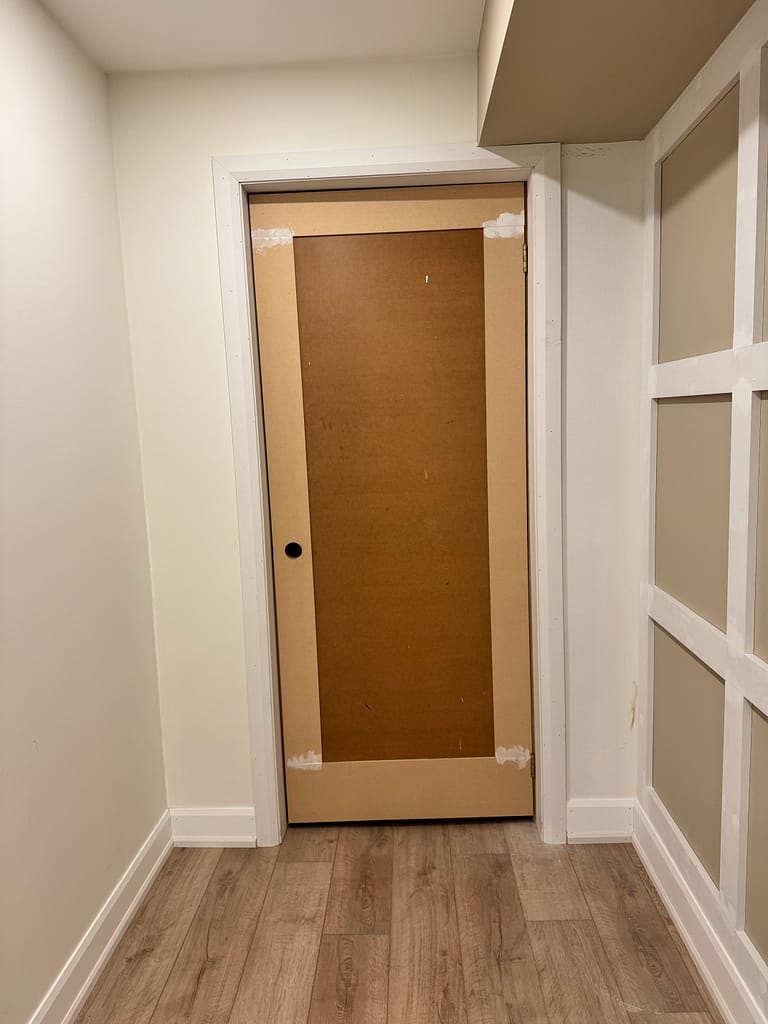 Custom panel detail added to a plain cold room door in a Milton basement to match the surrounding board and batten wall design.