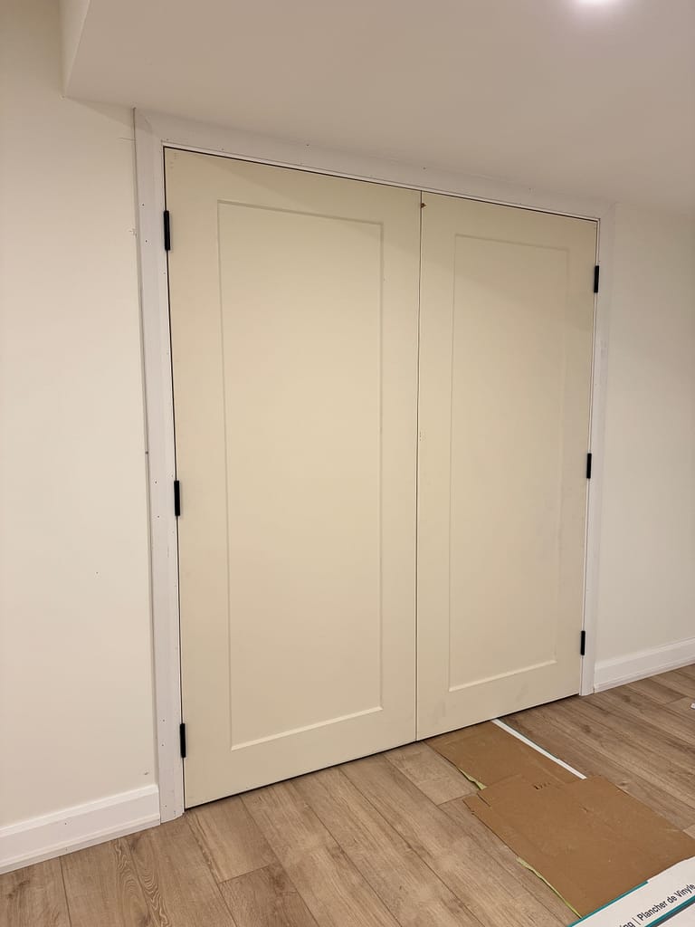 One-panel double doors installed in a Milton basement with casing and baseboard trim.