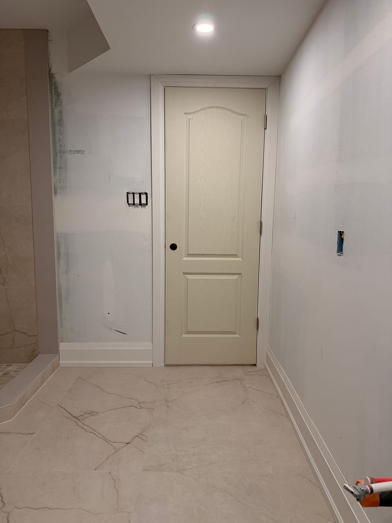 Molded two-panel basement door showing hardware position in relation to the middle lock rail.