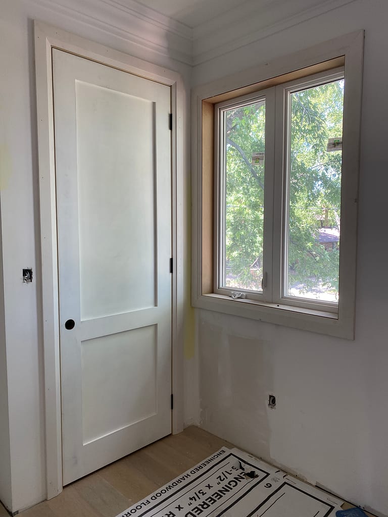 96-inch solid-core shaker door installed beside a window with custom jamb and casing work in Oakville.