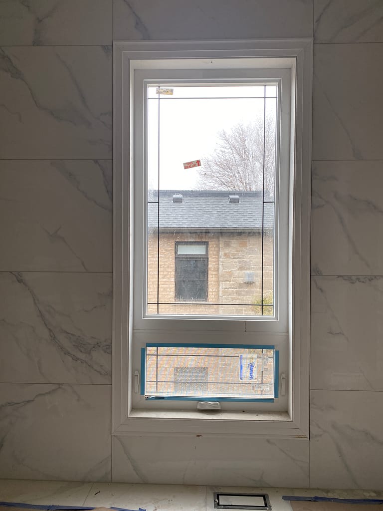 Bathroom window casing installed beside large tile walls in an Oakville custom home