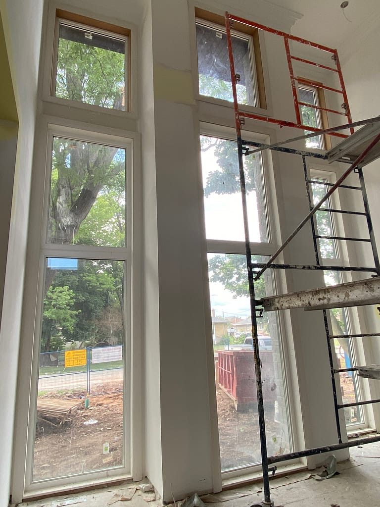 Tall window trim and extension work installed with scaffolding in a high-ceiling Oakville home.