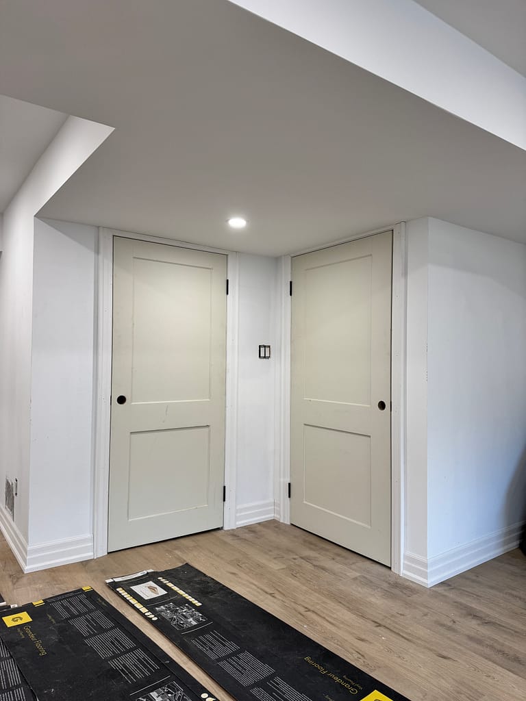 Two-panel basement doors showing how handle height can move away from the lock rail after a door is shortened.