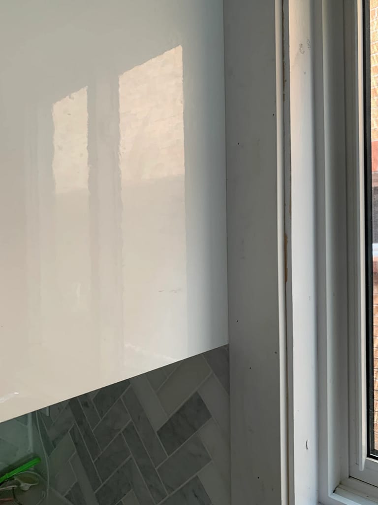 Close-up of new window casing fitted beside a kitchen cabinet and existing backsplash tile