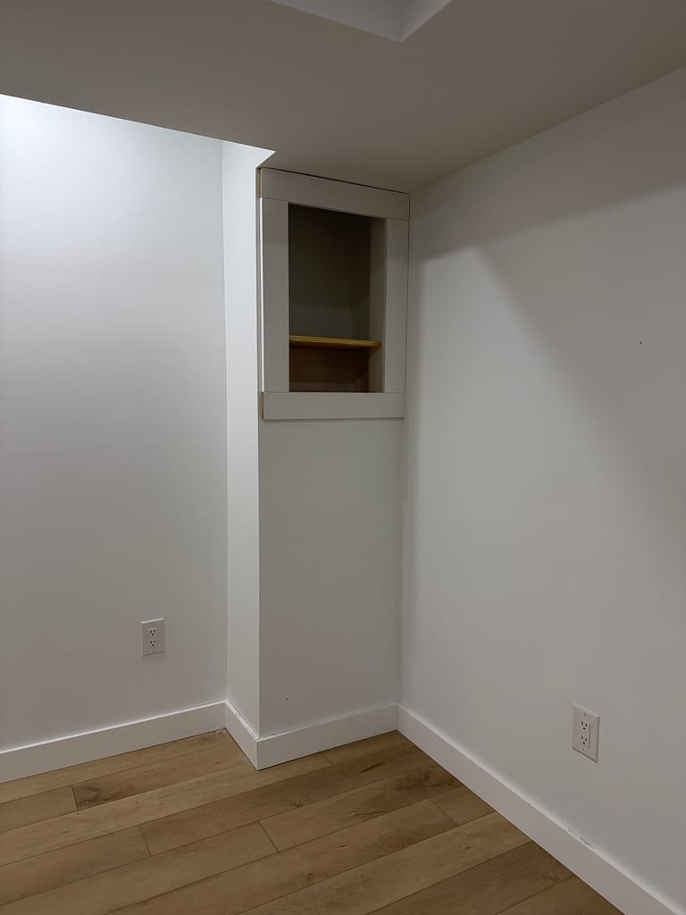 Built-in basement shelf framed with Craftsman-style flat-stock trim