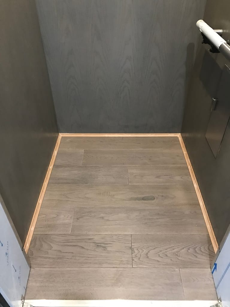Completed engineered hardwood flooring inside a home elevator in Mississauga