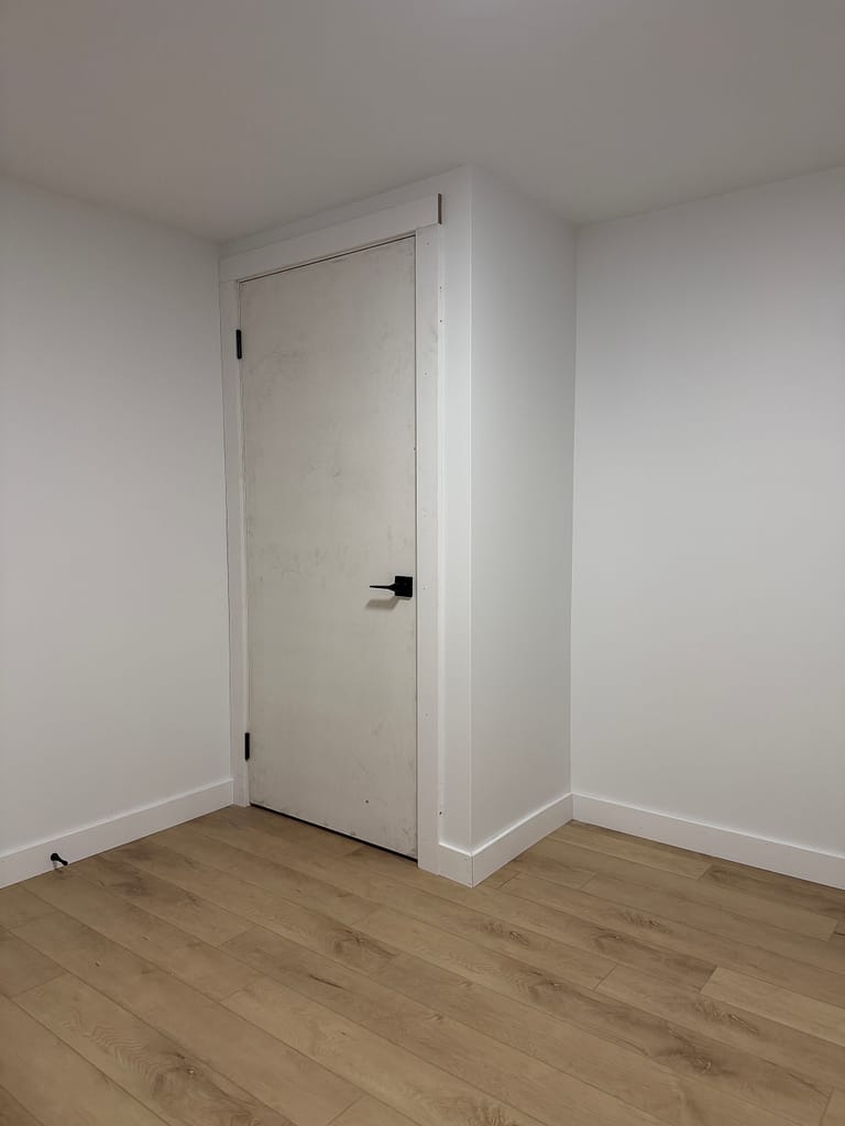 Custom-height flush interior door installed with black hinges and flat-stock casing