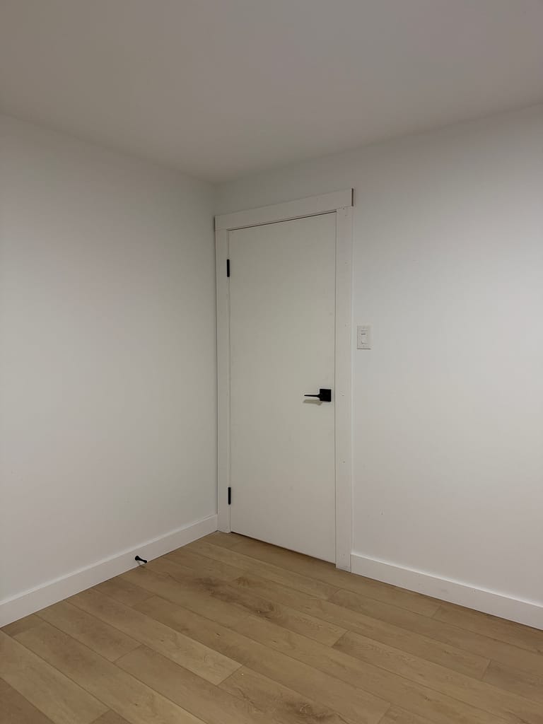 Basement room door installed with square casing and flat-stock baseboards in Hamilton