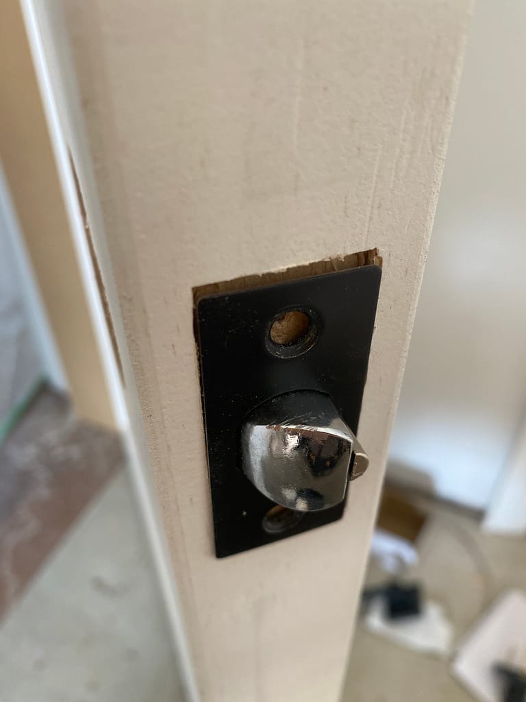 Close-up of an interior door latch bolt and black latch faceplate