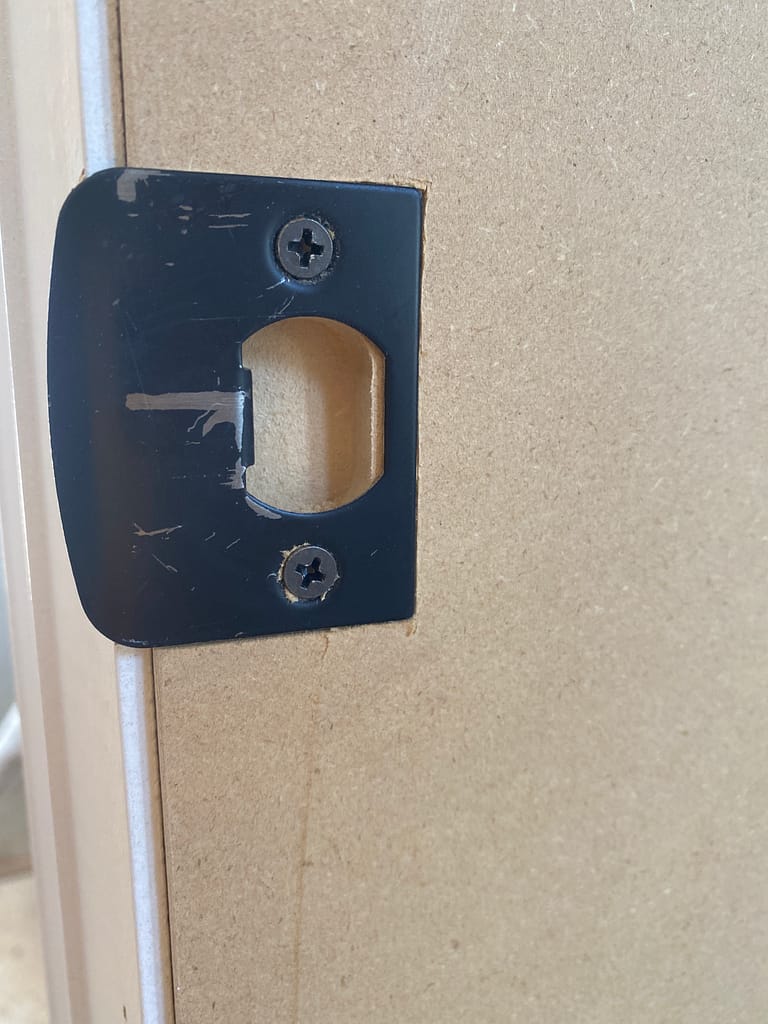 Close-up of a black strike plate installed on an interior door jamb