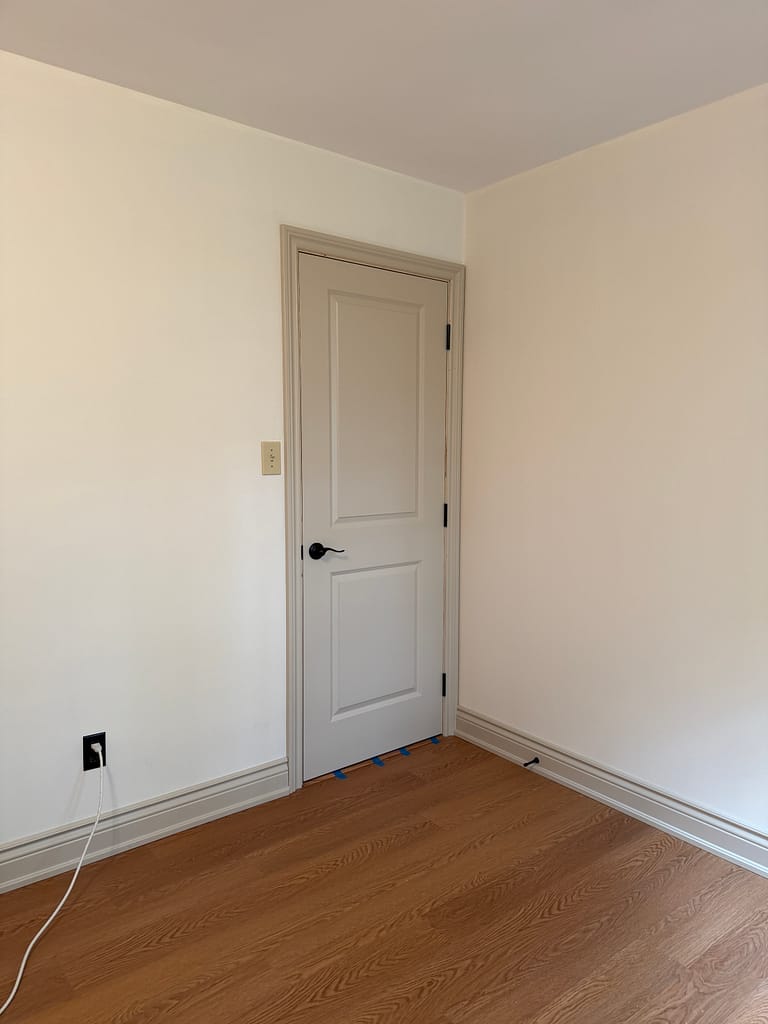 Prefinished two-panel interior door with casing, baseboards and vinyl flooring in a Milton bedroom