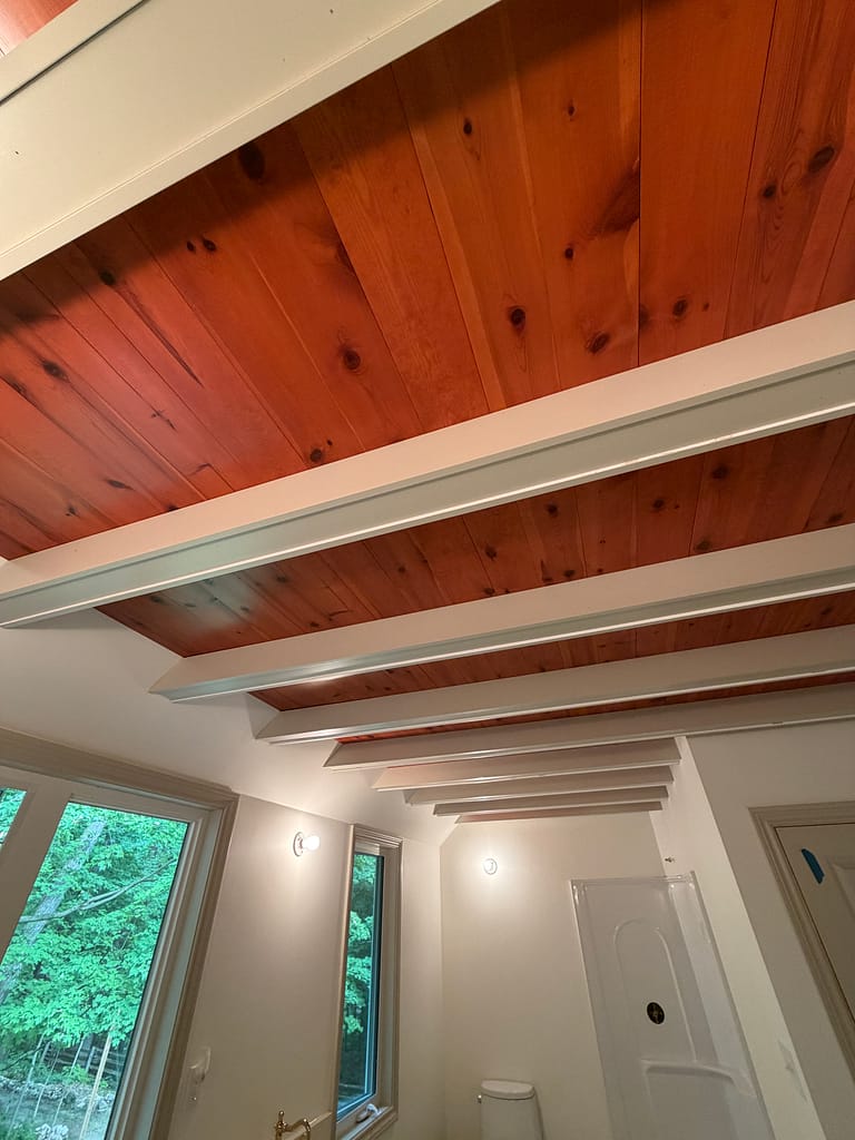 Close view of individually fitted painted beam covers against a natural wood ceiling