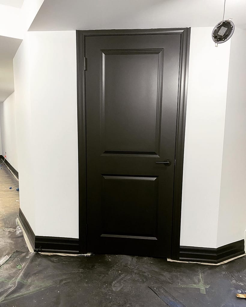 A modern interior door and trims painted in deep black with custom architectural hardware installed by finish carpenter Jack Ozer in Vaughan.