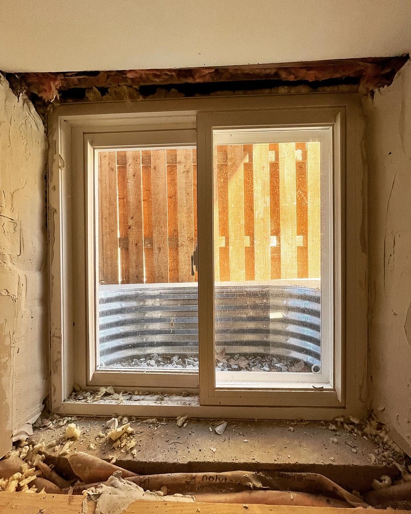 Basement window opening with construction debris visible.