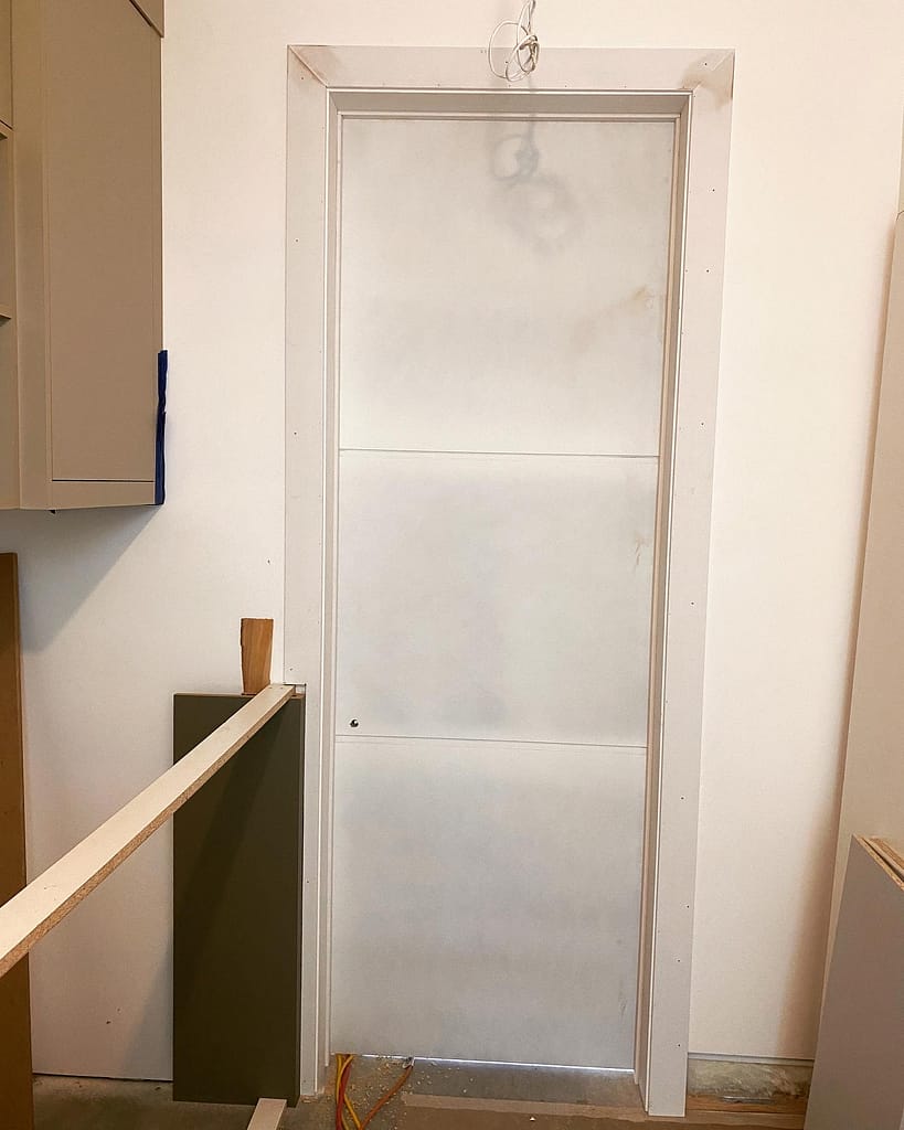 96-inch interior door installed with tall square casing beside unfinished cabinetry in an Oakville custom home.