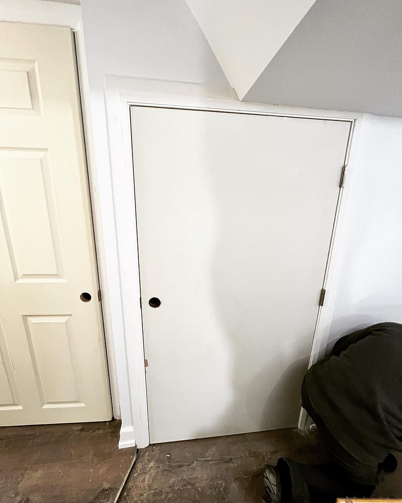 Plain slab door modified to fit a short basement storage opening beside an existing interior door.