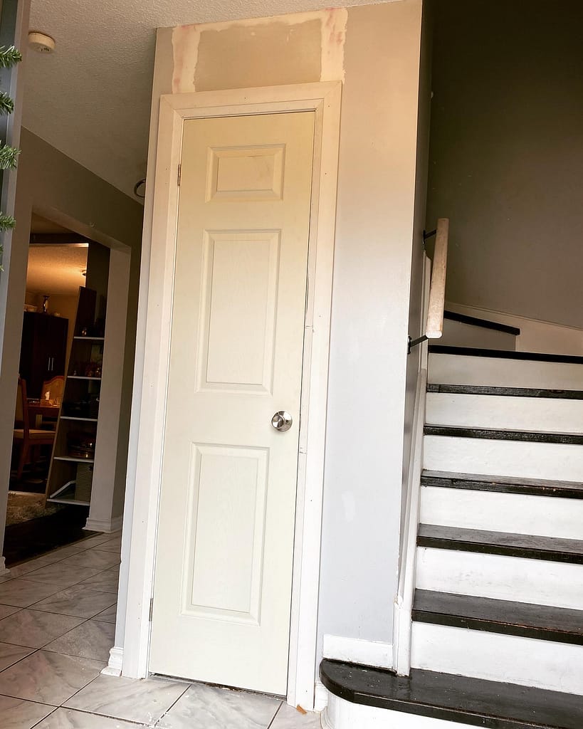 Panel closet door with casing installed while drywall joints are being finished above the opening