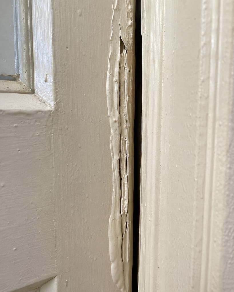 Heavy paint buildup on an old interior door edge causing the door to stick against the jamb.