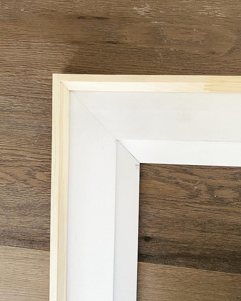 Close-up of a micro-pinned, pre-assembled modern bevel step door casing miter showing tight wood-to-wood structural tolerances.