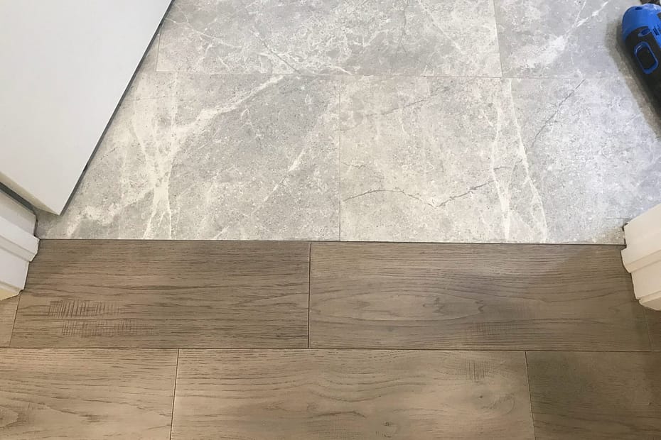 Completed engineered hardwood floor repair beside a tile transition in Mississauga