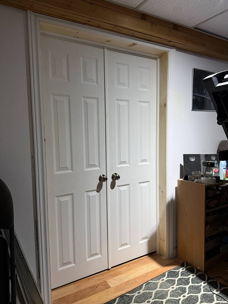 A finished view from outside the room of the new custom-fitted double slab passage doors and modern white casings installed by finish carpenter Jack Ozer.