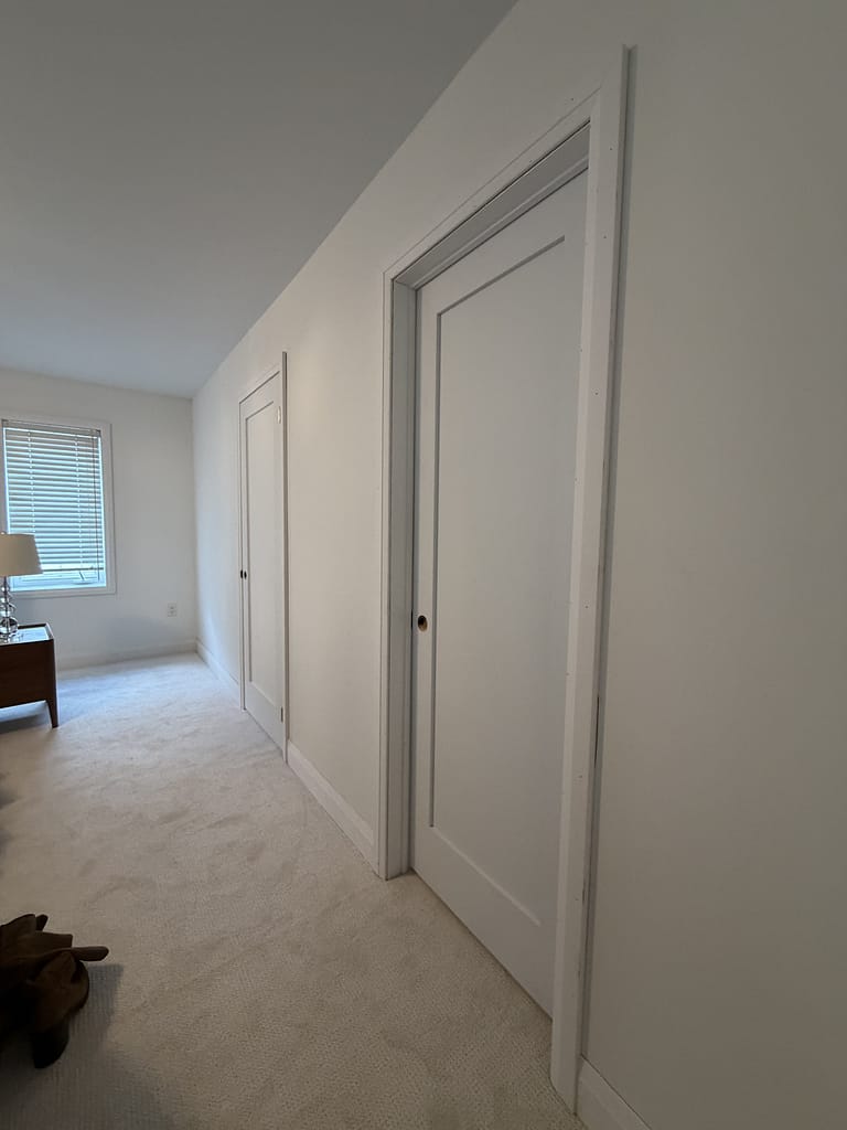 A finished view of the new white one-panel solid-core shaker doors installed with modern casing in Nicholle's Oakville home.
