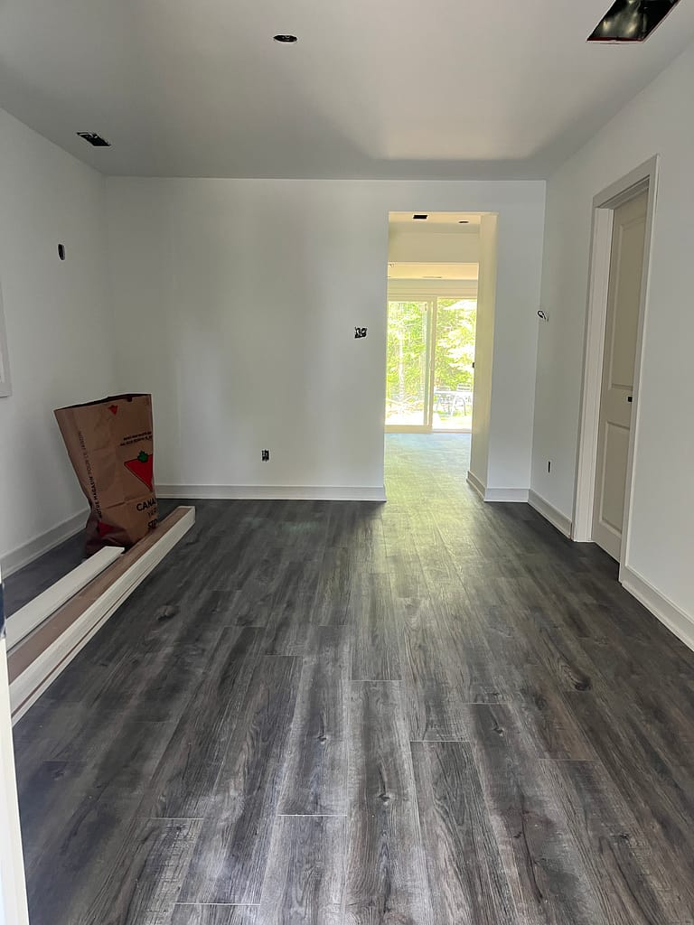 Baseboard installation and renovation finishing work in a Milton room with new flooring.