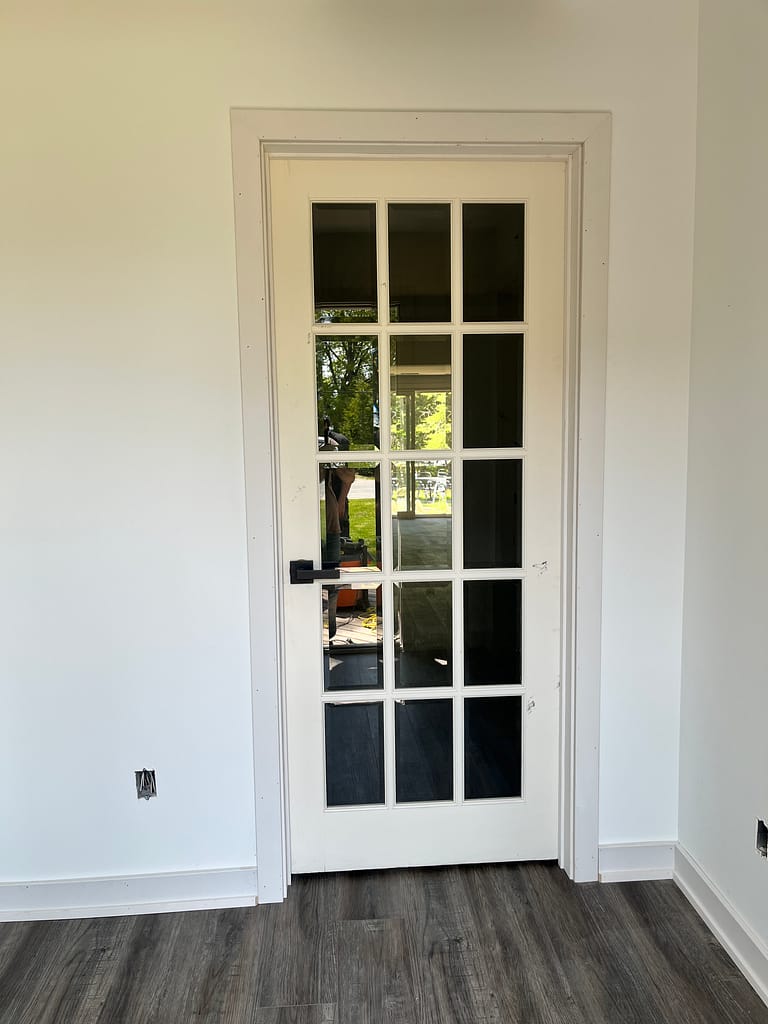 Glass interior door with casing, trim and baseboard installation in a Milton home renovation.