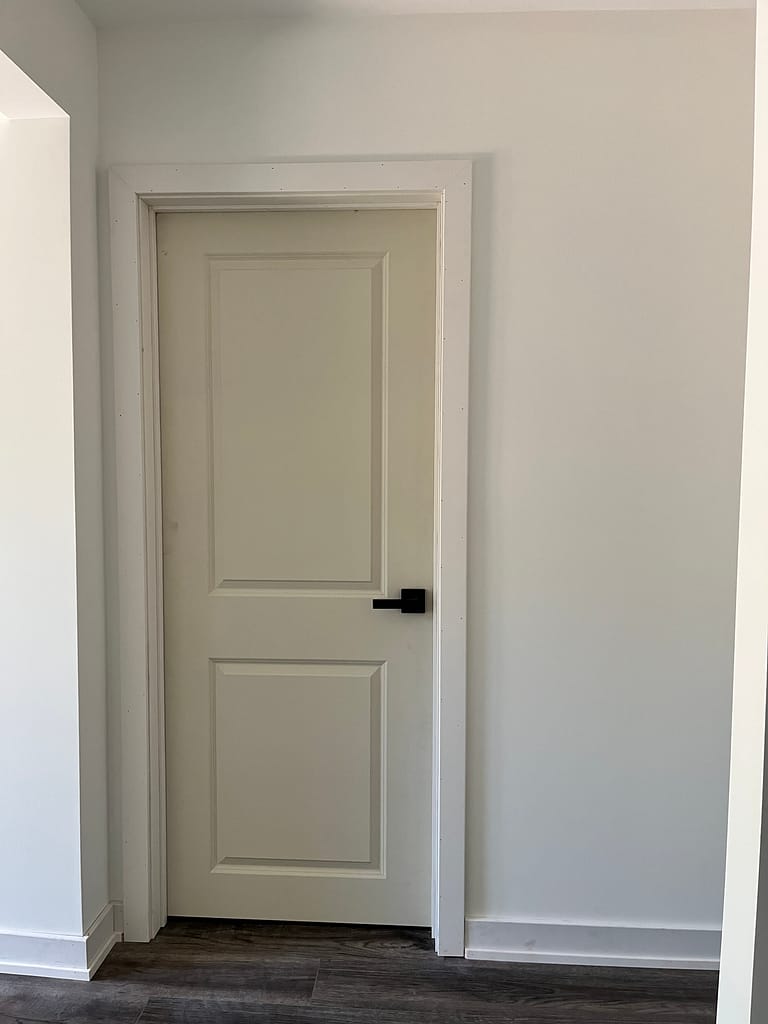 Interior door installation with casing, black hardware and baseboards in a Milton home.