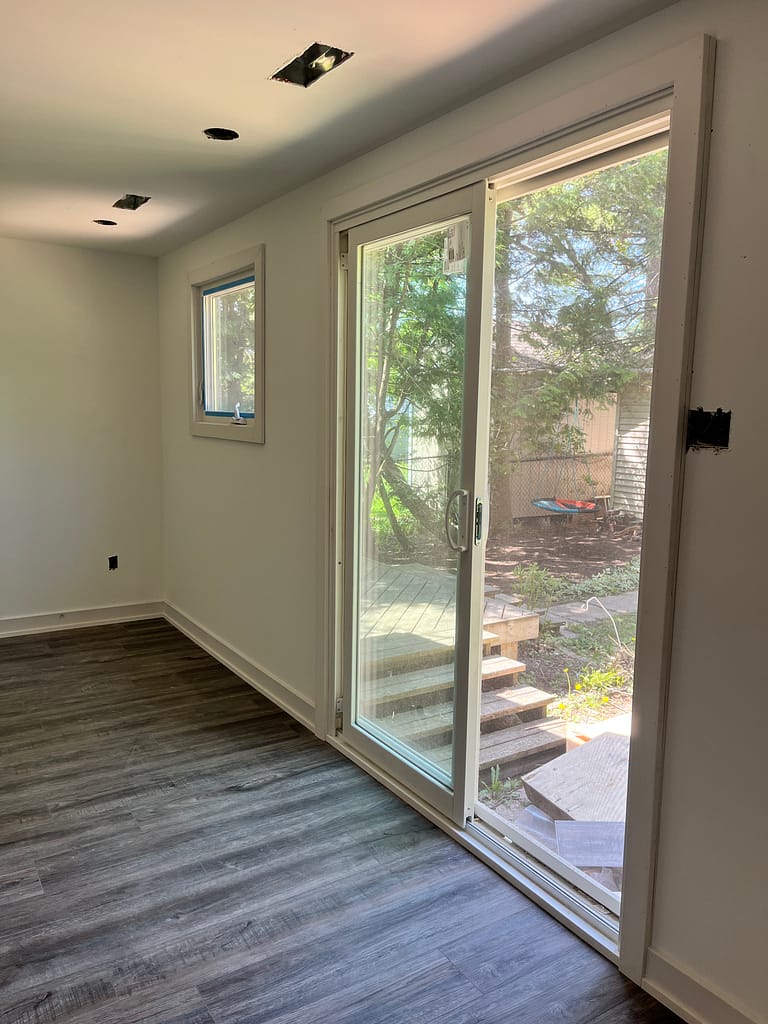 Patio door, window casing, baseboards and flooring installed during a Milton renovation finishing project.