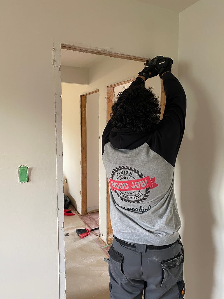 A finish carpenter removing an old door trim in an Oakville home