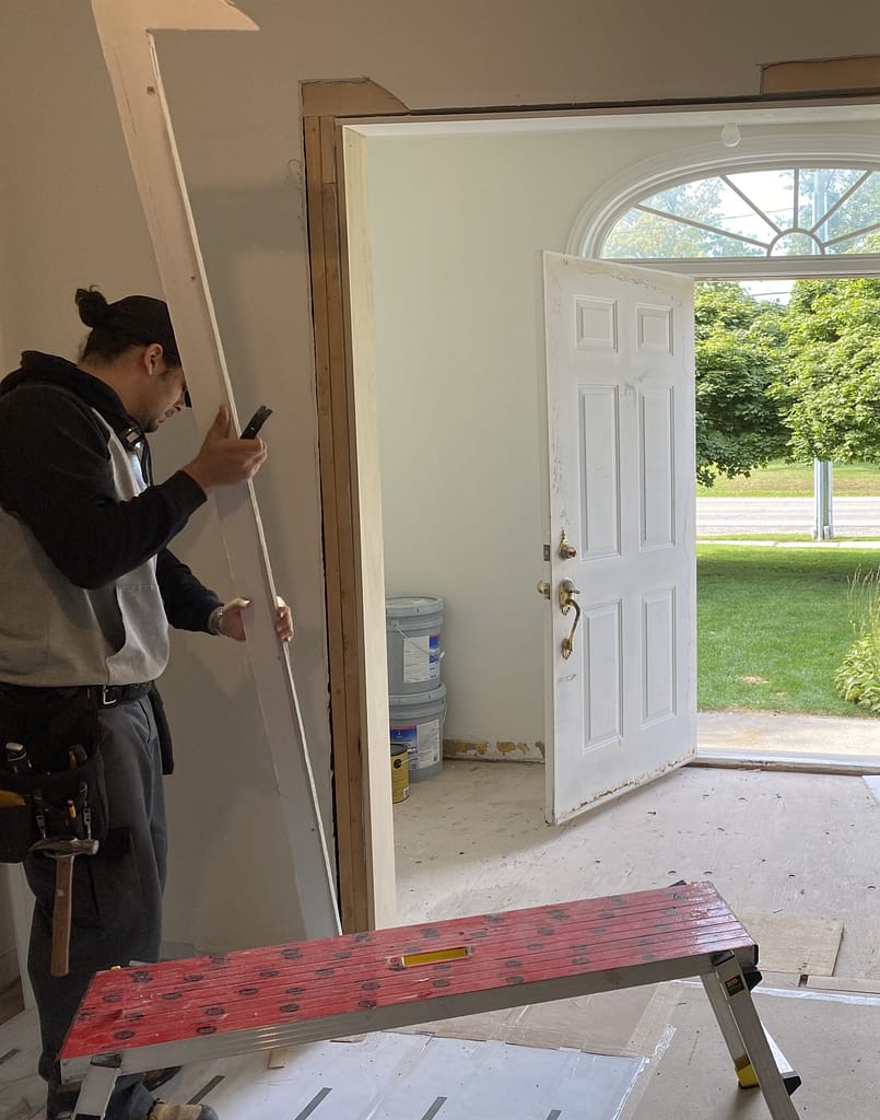 The finish carpenter is cutting the drywall for a proper trim installation in Oakville home