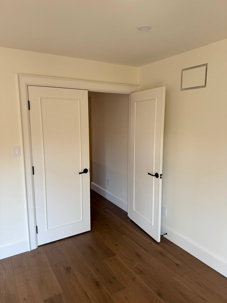 Painted custom double interior doors with long panel molding detail and black hardware.